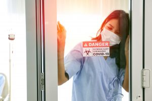 Woman behind glass with Covid sign