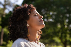 Young woman, face upturned to sun, eyes closed